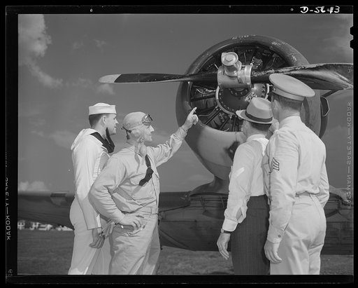 A poster comes to life. A couple of groundhogs get a liberal education from a Navy pilot as Aviation-radio Chief John Marshall Evans (left) escorts welder George Woolslayer and Sergeant French L. Vineyard (right) through his navy post. The three colleagues of the "Men Working Together" poster learne