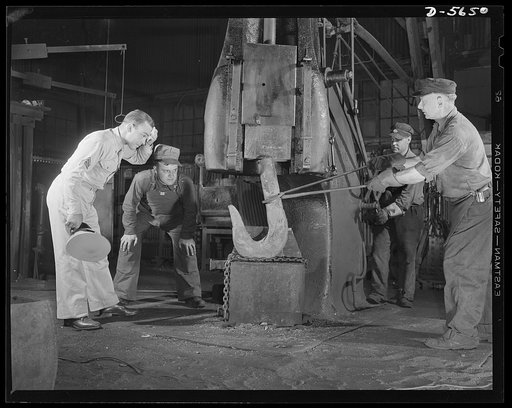 A poster comes to life. In a small blacksmith and maintenance shop on the mill grounds, Woolslayer and Sergeant Vineyard watch men at work on a drop hammer shaping a red-hot crane hook. Allegheny-Steel, Pittsburgh, Pennsylvania