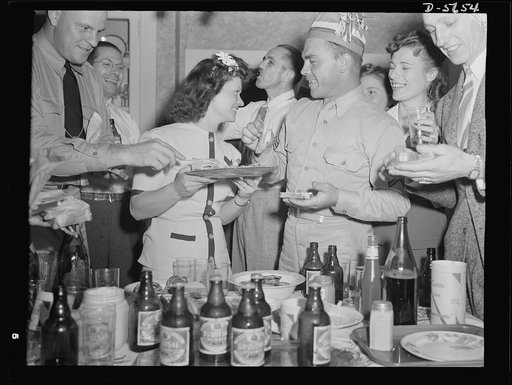 A poster comes to life. Another democratic institution, beer and pretzels. Chief radioman Evans, at extreme left, reached for a slice of the ham which Mrs. Woolslayer is serving. Sergeant Vineyard is wearing the paper hat. Allegheny-Steel, Pittsburgh, Pennsylvania