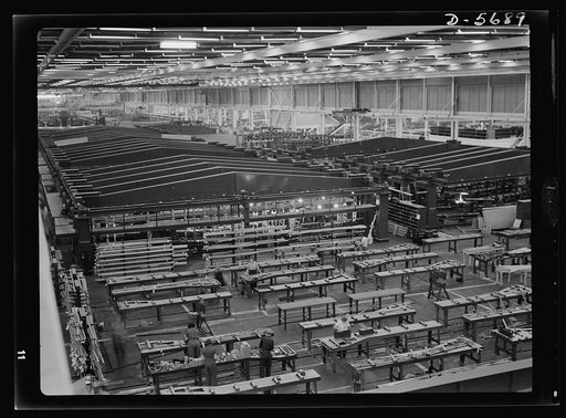 Production. Willow Run bomber plant. A small part of the world's largest one-story war production plant, the giant bomber factory at Willow Run, Michigan. Fixtures in background hold bomber wings during assembly. Ford plant, Willow Run