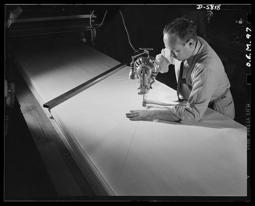 Production. Parachute making. As Louis Nerkin guides this cutting machine along the pattern lines, these layers of silk come one step nearer completion as parachutes. Pioneer Parachute Company, Manchester, Connecticut