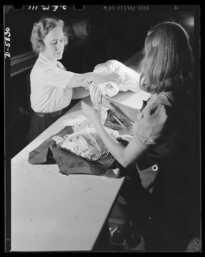 Production. Parachute making. The importance of proper folding and rigging of parachutes is well known to Adeline Gray, an employee of an Eastern plant, and herself a licensed rigger parachute jumper. Last summer she made the first jump in the first nylon parachute. Pioneer Parachute Company, Manche