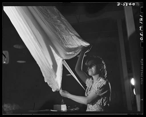 Production. Parachute making. With two aunts and an uncle in occupied France, Mrs. Delia Raymond makes careful inspection of flare parachutes which she hopes will help free her relatives. Of her work she says, "I like it. It's something so vital--it means so much and is so interesting. The country n