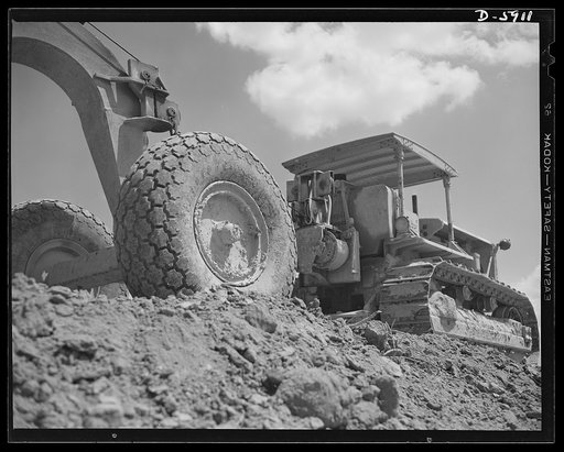 Fort Knox. Earth moving equipment. A huge carryall scraper and a powerful tractor work on a cut-and-fill job as a new access road is built at Fort Knox, Kentucky