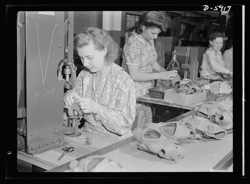 Women in industry. Gas mask production. Formerly employed in a vacuum cleaner plant, these young women are now making gas masks for America's soldiers and civilians. Margaret Reed, left, who used to work in the vacuum brush department, now operates a precrimping machine which attaches eye rings to t