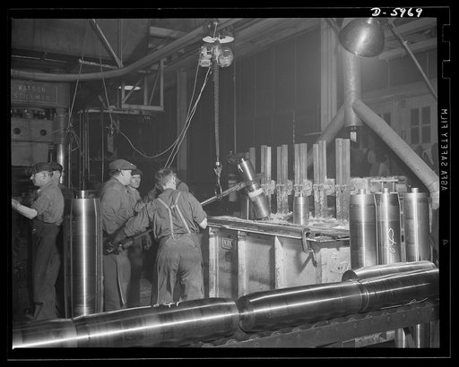 Production. 155mm shells. Heating 155mm shells in the salt bath of an Ajax furnace before nose forming operations are performed in a converted auto plant. Willy's, Toledo, Ohio