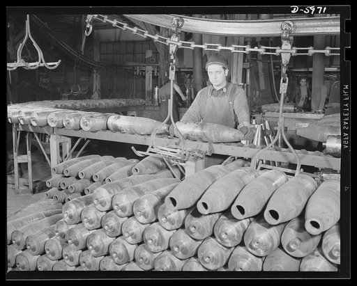 Production. 155mm shells. Removing 155mm shells from an overhead conveyor to cool after the nosing operation has been performed. From here they will be forwarded for shot blasting and finish turning. Site: a converted Midwest auto plant. Willy's, Toledo, Ohio