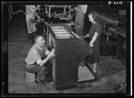 Conversion. Pianos to airplane motors. The lost chord won't be found till the war is over! One of the last electric organs to be made for the duration comes off the line in a Chicago factory now converted to war production. Note octagonal trainer-plane motor in background already undergoing assembly