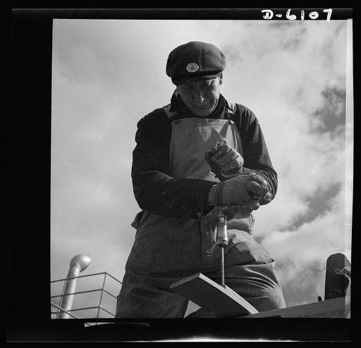 Production. Submarine chasers. Shipwrights preserve many hand skills. Brace and bit are needed to fit coamings to machine gun wings just aft of the wheelhouse of a wooden subchaser under construction in an Eastern boatyard. Marine Construction Company, Stamford, Connecticut