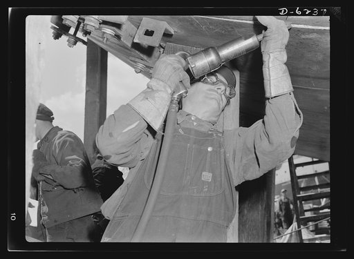 Production. Submarines. Mounting submarines on scaffoldings facilitates assembly. Here a worker rivets parts of the hull together