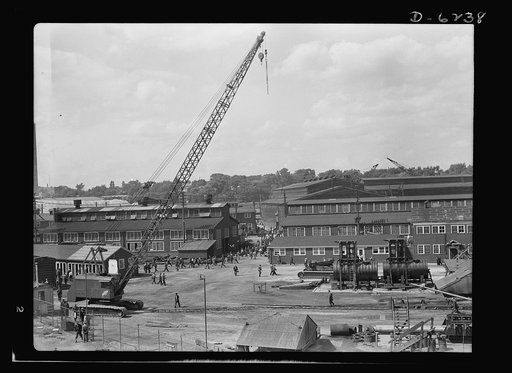 Production. Submarines. As the shift changes, workers pour out of the shipyards at Manitowoc, Wisconsin, where submarines are built on a twenty-four-hour day, seven-day week basis