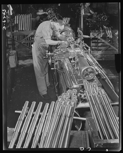 Production. Machine guns of various calibers. Walter Newman, operator of a high-speed lathe in a large firearms plant, performs an operation on the barrel of a machine gun. Many women workers are also employed in this plant in producing essential weapons for the armed forces