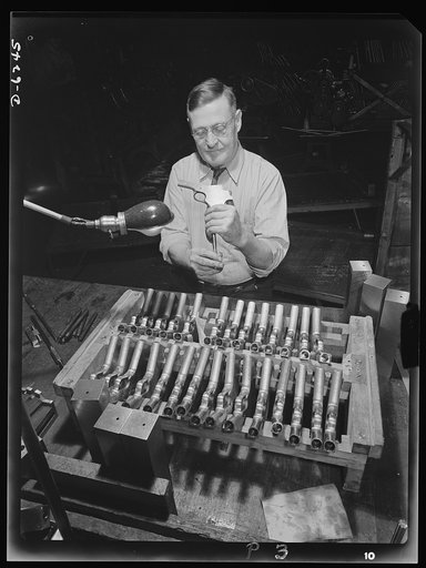 Production. 45-caliberautomatic pistols. William Watson gauges and inspects barrel drilling holes on .45-caliber automatic pistols in the plant of a large manufacturer of firearms. Many men and women are employed here in producing pistols, machine guns and other essential weapons for the armed force