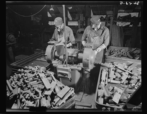 Production. Machine guns of various calibers. Grinding trunnion blocks for .50-caliber machine guns, produced in a large Eastern plant. Note how the operators are protected by respirators. Many women workers are also employed in this plant, producing essential weapons for the armed forces