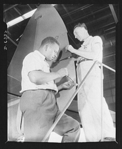 Americans all. In the armed forces and on the production line, Americans of every race and creed fight shoulder to shoulder to defeat the forces which threaten to destroy our liberties. Here Charles Geier (right) and Marcell Webb work on the rudder of a P-47 pursuit ship in an Eastern aircraft facto