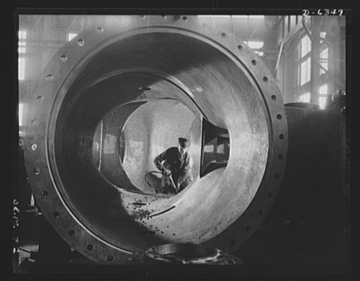 Production. Locomotives. Framed by a huge hydraulic turbine runner, this worker uses a pneumatic hammer to remove irregularities from its inner surface. This is an important operation, since a smooth waterway must be provided through the runner. Baldwin Locomotive Works