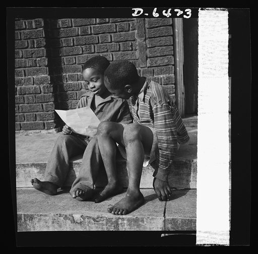 Manpower, junior size. Two barefoot junior commandos in Roanoke, Virginia, wriggle their toes with delight as they study their instructions for collecting scrap for Uncle Sam's great army. Directions for the scrap collection were given to the children at the huge star-spangled rally that launched th