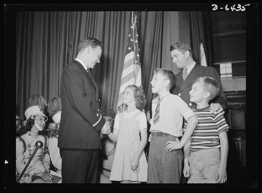 Manpower, junior size. A treat for the junior commandos of Roanoke, Virginia! Ensign Andrew Blair, U.S. Navy Reserves extends congratulations to the youngsters at their scrap rally for their whole-hearted efforts to collect material for Uncle Sam's armed forces