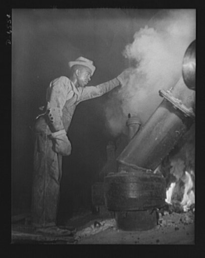 Tennessee Valley Authority production. Elemental phosphorus. A Negro worker tending an electric phosphate smelting furnace which is producing elemental phosphorus at a TVA chemical plant in the Muscle Shoals area. The phosphorus, used in the manufacture of incendiary bombs and shells and of material
