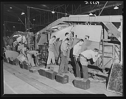 Production. Lockheed P-38 pursuit planes. A complete center section for a Lockheed P-38 pursuit plane in an assembly jig at a large Western aircraft plant. On the final line, the entire center section will be joined to other plane sections, and noses, engines, wings, landing gear and other equipment