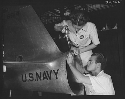 Naval air base. Corpus Christi, Texas. Mrs. Virginia Davis, a riveter in the ssembly and repair department of the naval air base in Corpus Christi, Texas, supervises Charles Potter, a National Youth Administration (NYA) trainee from Michigan. After eight of training, he will go into the civil servic