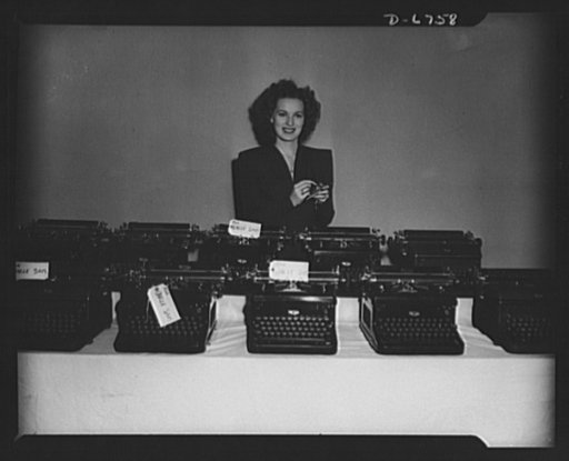 The stories they've told! Another load of RKO Radio typewriters is turned in to the government for war work. Somewhere in the lot is Maureen O'Harra's personal typewriter which she added to the pile before she would pose in the picture. The machines come from the script department where each one has