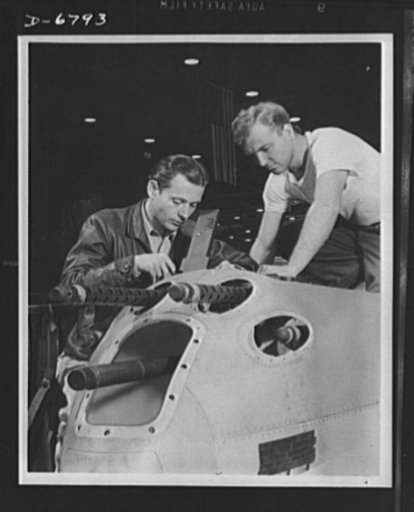 Production. Lockheed P-38 pursuit plane. An armorer and his assistant check the installation of guns in a nose section of a new Lockheed P-38 pursuit plane. As the ship travels from one station to another along the main assembly line, wings, engines, armament and other essential equipment are instal