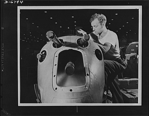 Production. Lockheed P-38 pursuit plane. An armorer's assistant in a large Western aircraft plant works on the installation of one of the machine guns in the nose section of a new Lockheed P-38 pursuit plane. This nose section will later be "mated" to a center section and the plane body will travel 