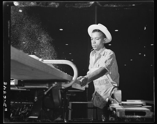Production. Motor torpedo boats (wooden). A Negro carpenter at a Southern shipyard runs a heavy plank through a power saw. He works on the building of seventy-eight-foot wooden torpedo boats which are produced in great numbers at this yard. The hulls of these speedy motor-driven boats are built indo