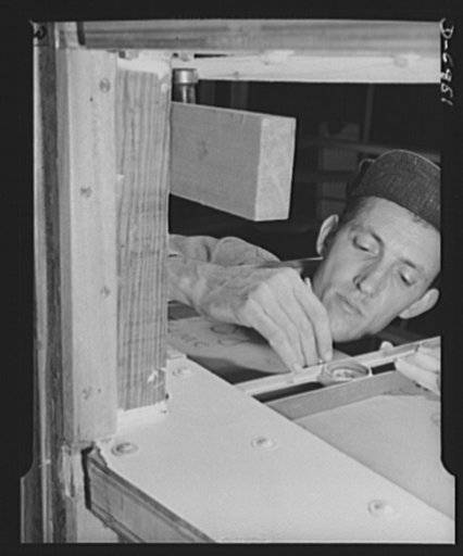 Production. Motor torpedo boats (wooden). A carpenter at a Southern shipyard checks the framing of a new seventy-eight-foot motor boat. The hulls of these speedy wooden boats are built indoors of prefabricated parts and sections and are then moved to nearby water for launching and fitting. Higgins I