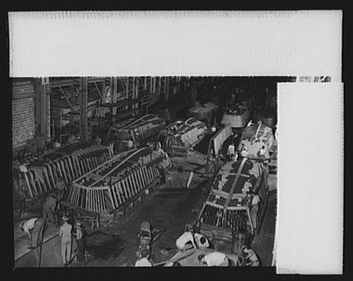 Production. Small ramp boats. Small wooden ramp boats for landing men and equipment on beaches, under construction at a Southern shipyard. The frames of these thirty-six-foot carriers are made of prefabricated parts and sections. The completed boats are launched by crane and delivered in tows of six