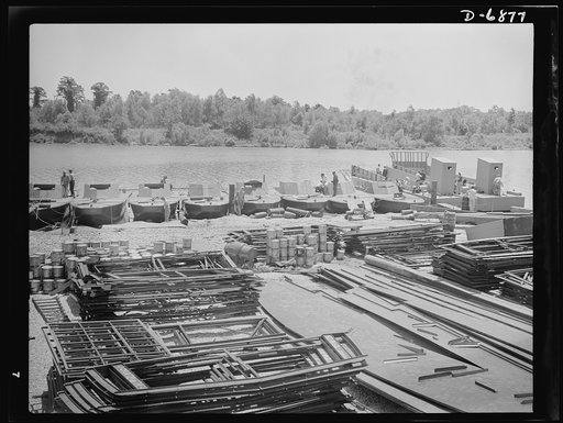 Production. Fifty-foot steel ramp boats. Steel ramp boats, fifty feet long, powered by twin diesel engines, are being made in great numbers at a large Southern boat building yard. Two of the ramp boats, one with the ramp partly lowered, shown at the right. The materials in the foreground are for the