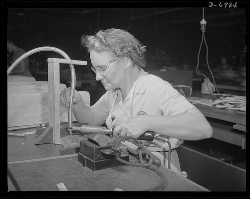 Production. B-25 bombers. Soldering an end fitting to a flexible conduit that will carry some of the complicated electrical wiring of a B-25 bomber. The Western plant in which this warship of the air is built employs many women at jobs that once were considered exclusively the work of men. Fairfax b