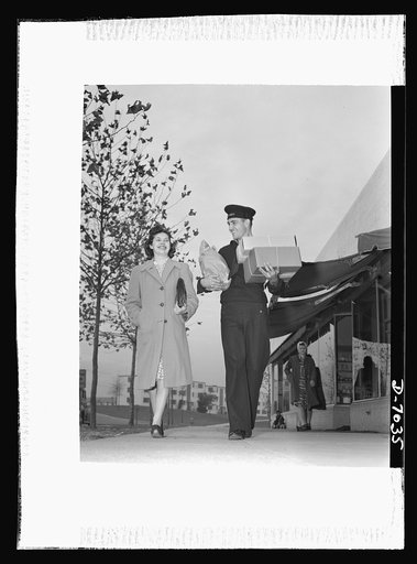 I'll carry mine. As patriotic on leave as he is on shipboard, this sailor on furlough keeps America's wartime pledge to save tires and gasoline by carrying the family purchases. Note that the young man's wife carries only her own handbag: husbands please observe