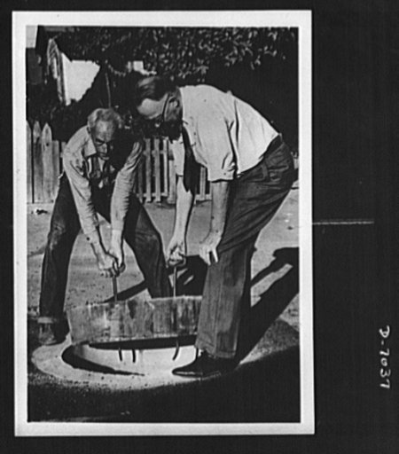 Conservation. Wooden manhole covers. Lifting a wooden manhole cover into place is Colonel Carl H. Reeves, superintendent of the Los Angeles County, California, Maintenance Department. Treated to resist termites and decay, each wooden cover saves 500 pounds of metal. It may be manufactured without th