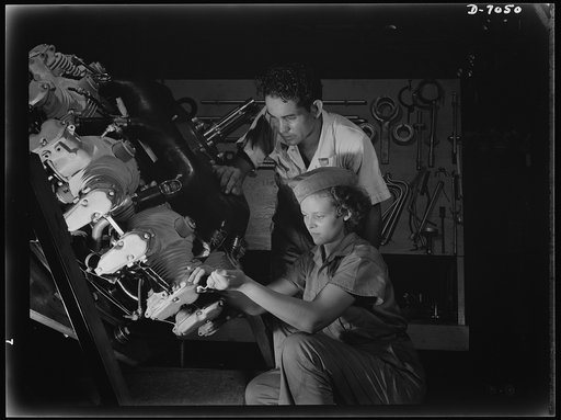 Naval air base, Corpus Christi, Texas. Now an expert mechanic, Mary Josephine Farley shows an National Youth Administration (NYA) trainee the tricks of a Wright Whirlwind Motor. He will act as her helper for about eight weeks; then he'll be qualified to work on motors for the naval air base at Corpu