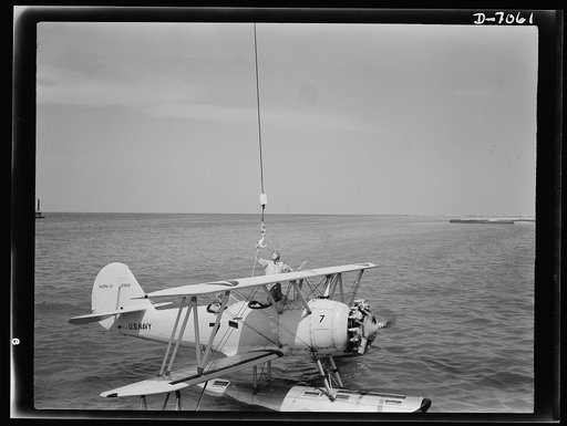 Naval air base, Corpus Christi, Texas. Coming under the "hook" is the first step in getting a sea plane on land. The ship is then hoisted out of the water and placed onto a dollie on shore and wheeled to the hangar. The plane is an N3N, Navy training ship, stationed at the naval air base in Corpus C