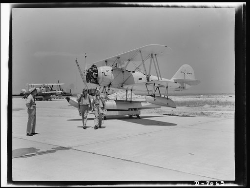 Naval air base, Corpus Christi, Texas. Flight's over--an N3N training plane is safe on the dollie and pilot and instructor go back to the hangar. After fulfilling their service schedules, planes at the Corpus Christi, Texas, naval air base are completely reconditioned by civil service mechanics atta