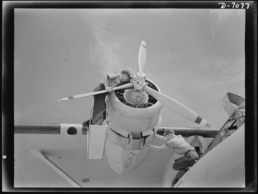 Naval air base, Corpus Christi, Texas. Perched at the nose of a Navy PBY flying ship, two sailors check the huge motor to keep them in first class condition while the plane is in service. These men are aviation mechanics nates stationed at the Naval Air Base in Corpus Christi, Texas