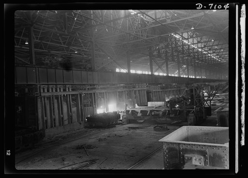 Salvage. Scrap for steel mills. Charging boxes loaded with scrap metal are dumped into electric furnaces where the scrap is melted down with steel and fluxing materials. Workers here wear dark glasses to protect their eyes from the glare