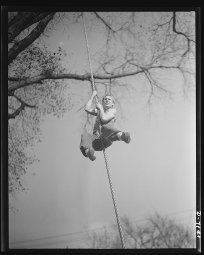 High school Victory Corps. In true commando style, this young student at Flushing High School, Queens, New York, is learning to take care of himself no matter what the circumstances may be. High cliffs and walls won't stop him when he is old enough to serve in the armed forces