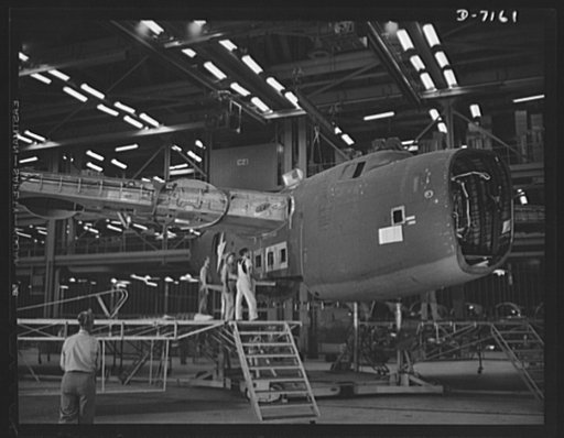 Production. B-24 bombers and C-87 transports. Mated fuselage, nose and wing center sections of a consolidated transport plane are lowered as a unit into the carriage on which the shell will travel along the final assembly line. This new transport, an adaptation of the B-24 bomber, is known as the C-