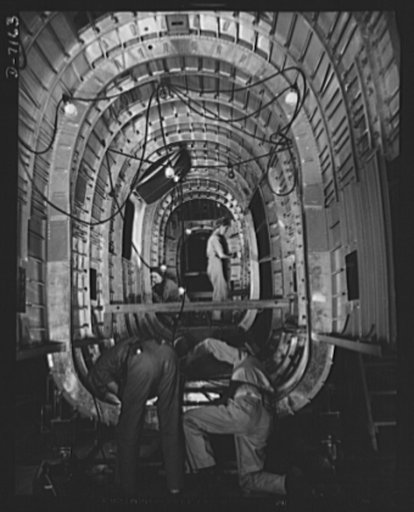 Production. B-24 bombers and C-87 transports. Structural parts of a consolidated transport plane are installed in the "tunnel" of a tail fuselage section in a Western aircraft plant. This new transport, an adaptation of the B-24 bomber, is known as C-87, and carries one of the greatest human or carg