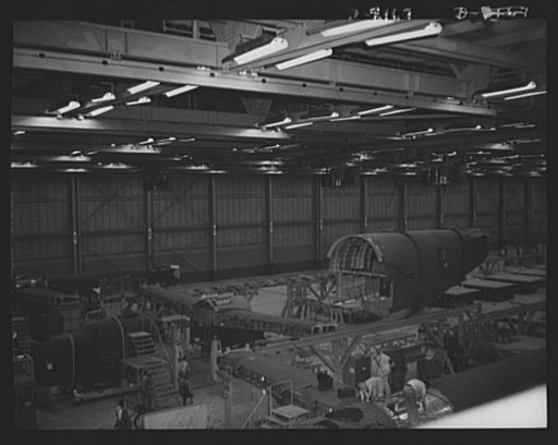 Production. B-24 bombers and C-87 transports. A tail fuselage for a consolidated B-24 bomber is being lowered to place in a fuselage meting fixture at a Western aircraft plant. Here, tail fuselage, wing center section and nose section are joined. This bomber carries a heavy bomb load and is capable 
