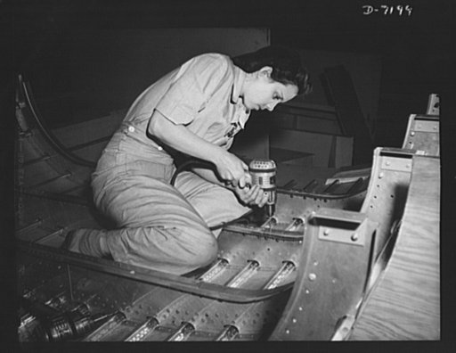 Production. B-24 bombers and C-87 transports. Juanita Reviers, expert aircraft mechanic, uses a portable electric drill on the belly covering of a consolidated transport plane converted from a B-24 bomber. These new transports, now going down the production lines of a big Western plant, carry one of