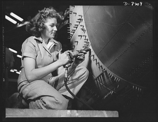 Production. B-24 bombers and C-87 transports.  A girl mechanic in a large Western aircraft plant rivets the belly of a new consolidated transport plane. The Cleco fasteners which protrude from the surface hold the sections of metal in place while the riveting job is being done. This new transport, a