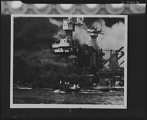 Pearl Harbor bombing. Seaman rescued. A small boat rescues a seaman from the 31,800 ton USS West Virginia burning in the foreground. Smoke rolling out amidships shows where the most extensive damage occurred. Note the two men in the superstructure. The USS Tennessee is inboard