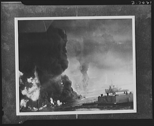 Pearl Harbor bombing. Burning oil. Streaming from the shattered fuel tanks, oil turned parts of Pearl Harbor into a sea of flames, following the Japanese attacks. This picture was taken from near the naval air station boat landing. Barely visible through the smoke area are a damaged U.S. battleship 