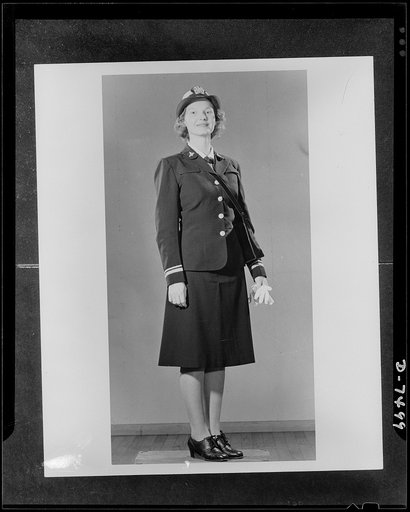 WAVES (Women Accepted for Voluntary Emergency Service). Lieutenant Marion Enright, U.S. Naval Reserve, poses in dress blues and white cap cover. Her stripes are blue instead of traditional gold. WAVES carry white gloves and wear a black leather strap purse