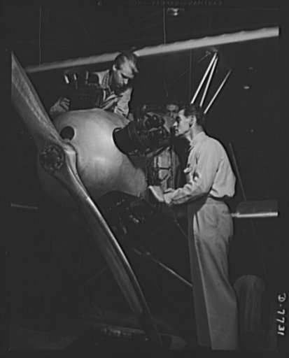 High school Victory Corps. Rudolph Angar, instructor aeronautics at Washington High School, Los Angeles, California, checks an airplane engine that two of his students put together. Future plane mechanics, the boys and girls of the class work with actual plane parts
